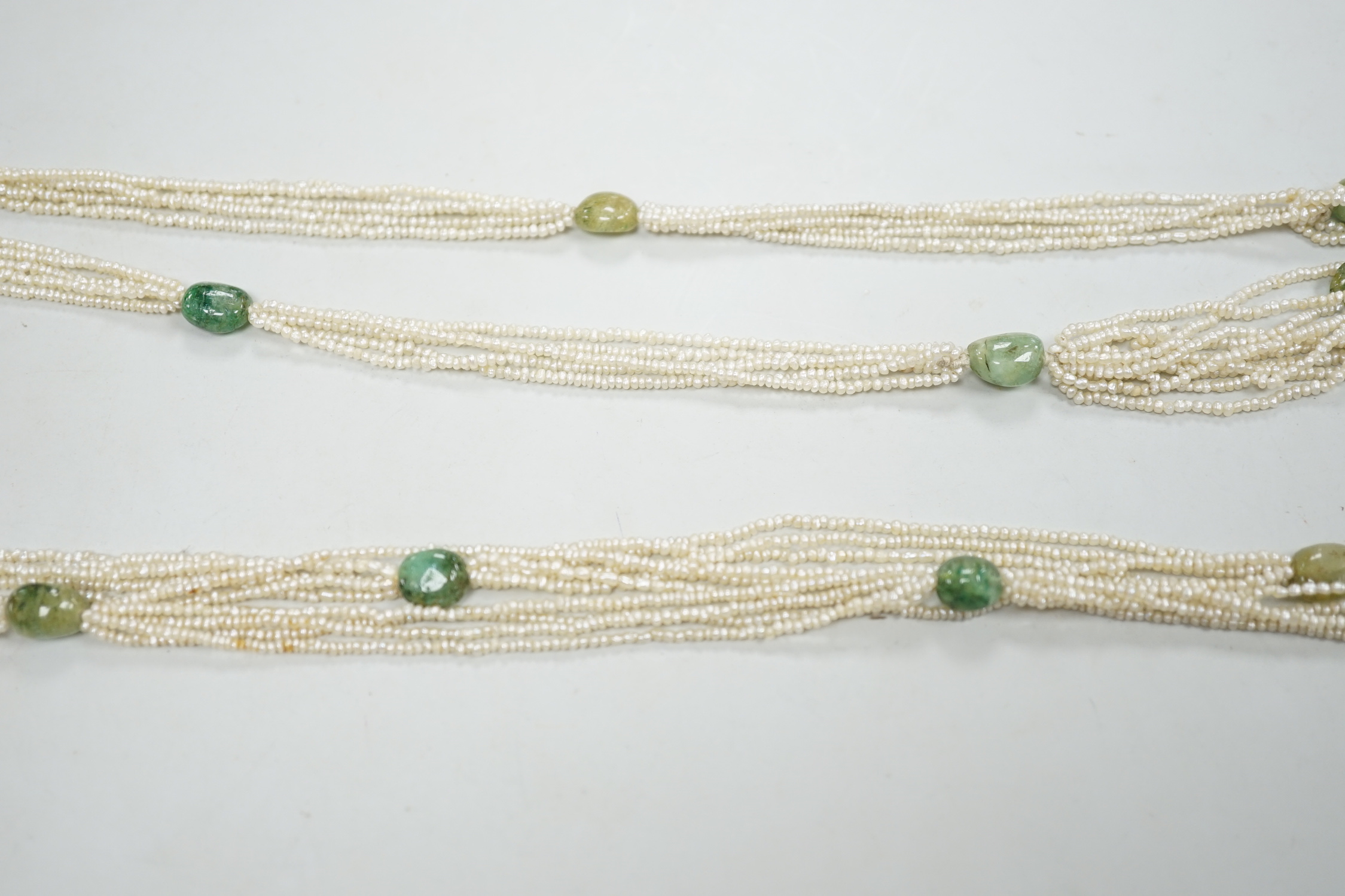 A 19th century Indian multi strand seed pearl and emerald? set long necklace, with gem set tassel drops, 176cm.